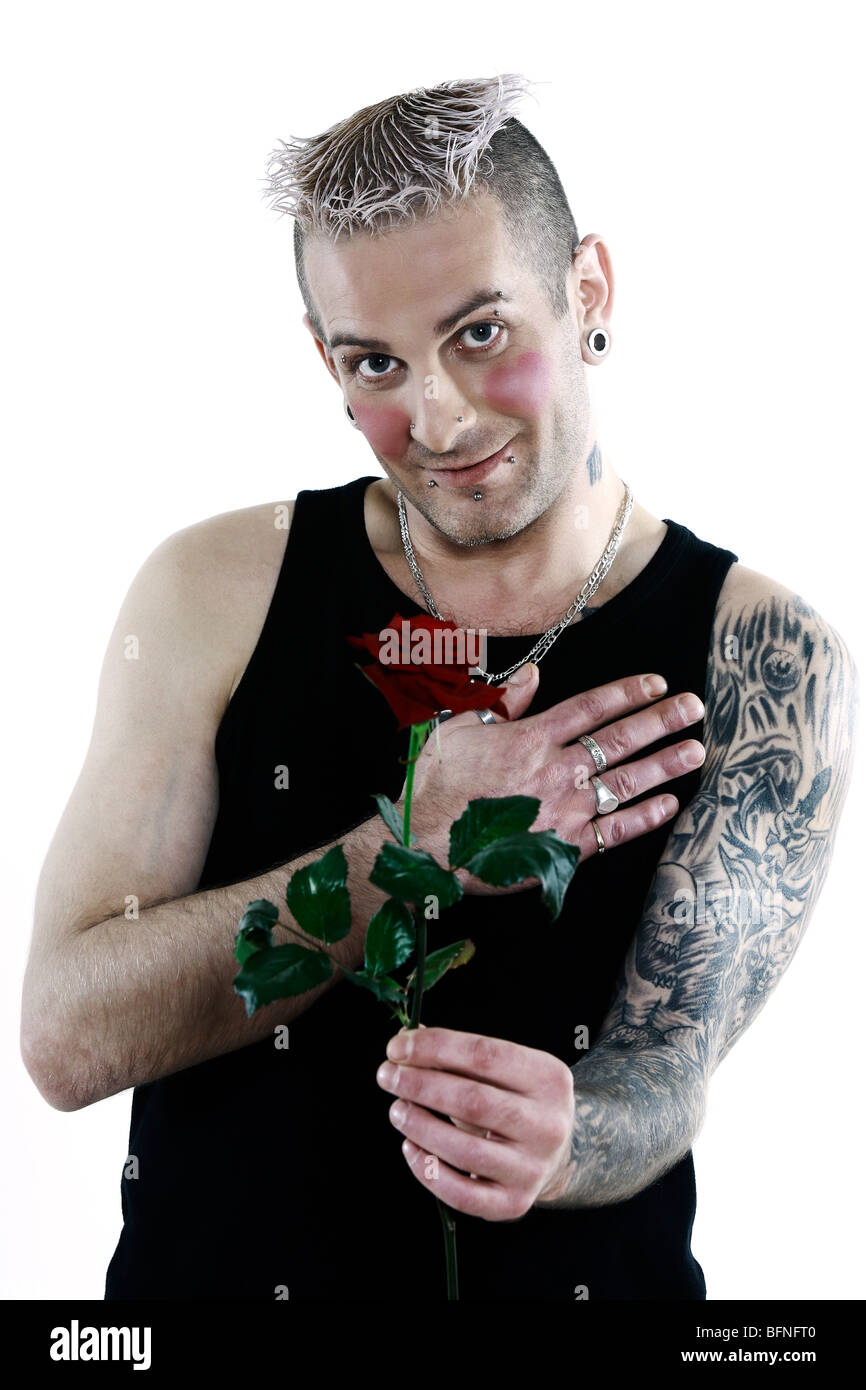 Studio shot blushing romantique coeur timide avec tatouage et piercing tenant une rose Banque D'Images