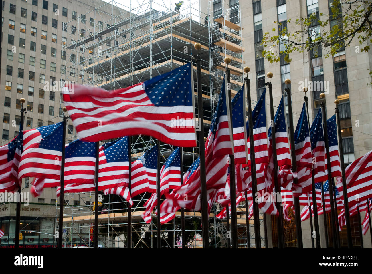 Derrière un écran d'un des drapeaux américains entourant la Rockefeller Plaza à New York décorent les travailleurs du plus célèbre arbre de Noël Banque D'Images
