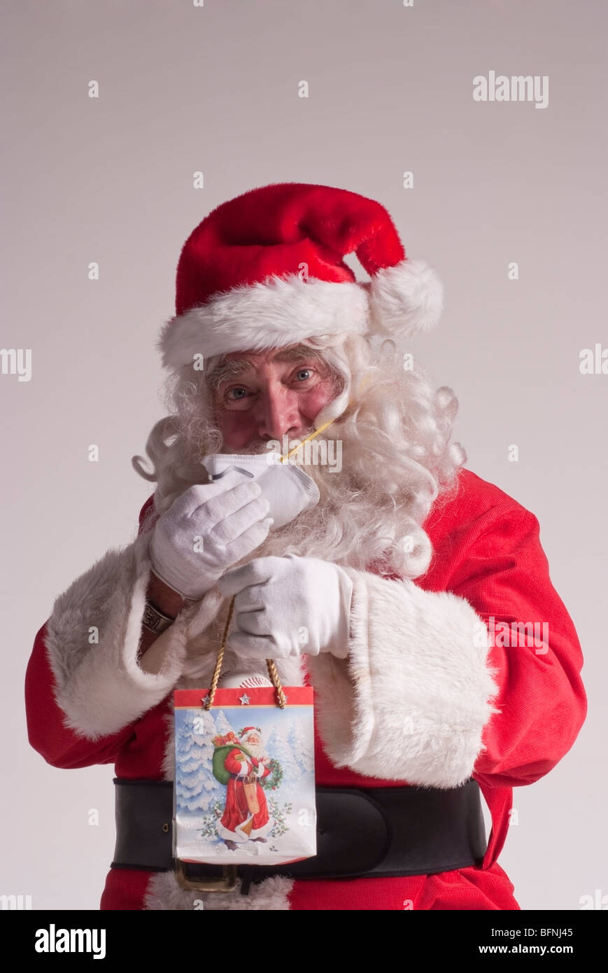 65-year-old man dressed as Santa Claus Noël pour mettre sur un masque respiratoire de protection contre le virus H1N1 (grippe porcine) Banque D'Images