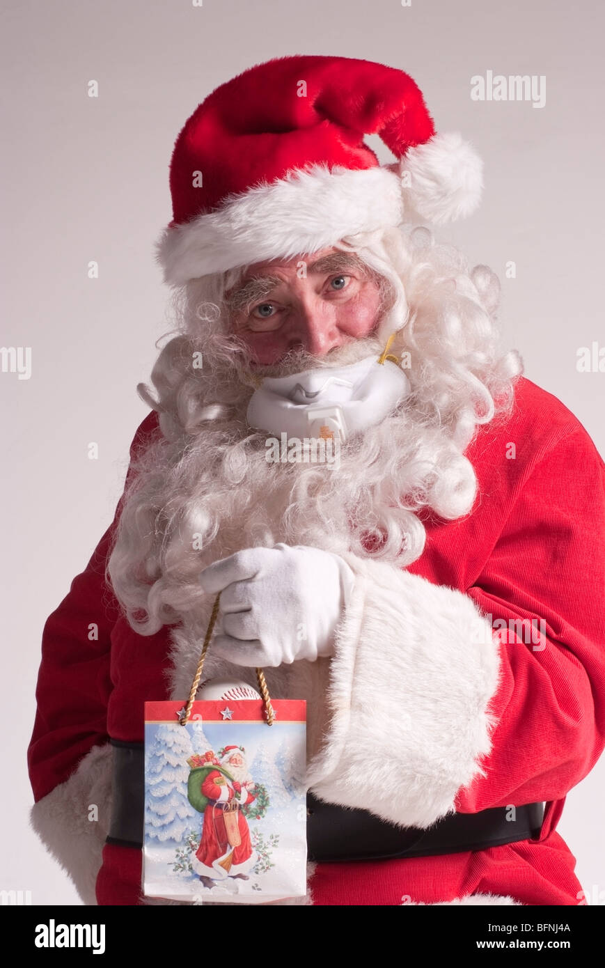 65 ans, homme habillé en père Noël pour Noël portant un masque respiratoire de protection contre le virus H1N1 (grippe porcine) Banque D'Images