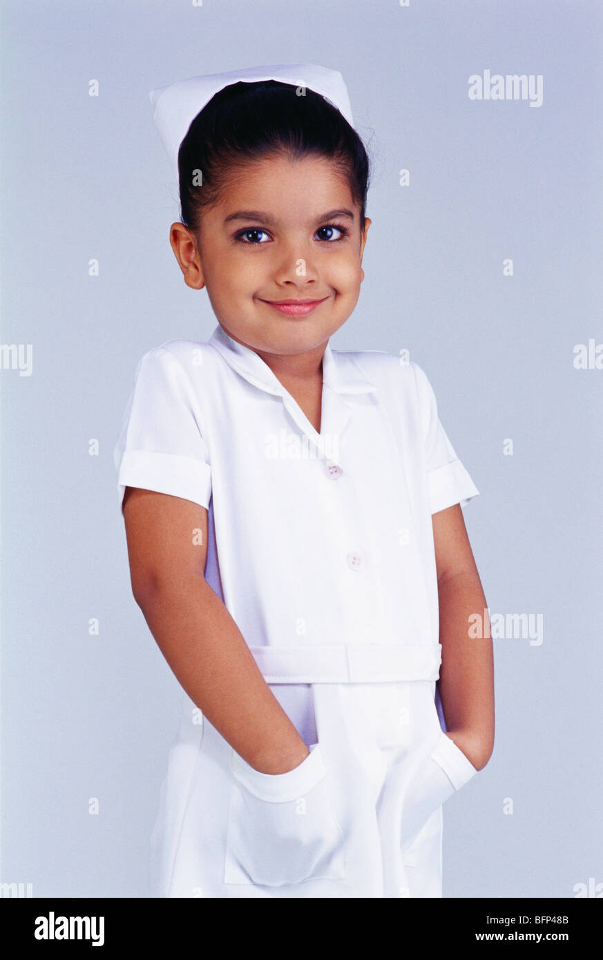 Enfant indien fille en costume de fantaisie d'infirmière avec les deux mains dans les poches ; Inde ; Asie ; MR#497 Banque D'Images