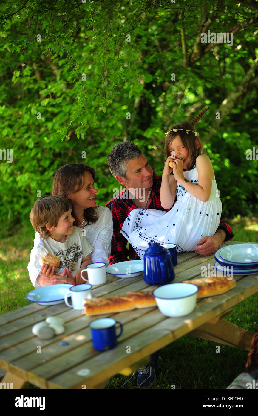 A family sitting avoir du pain et le déjeuner en plein air dans l'air frais, sur un camping à Cornwall. Banque D'Images
