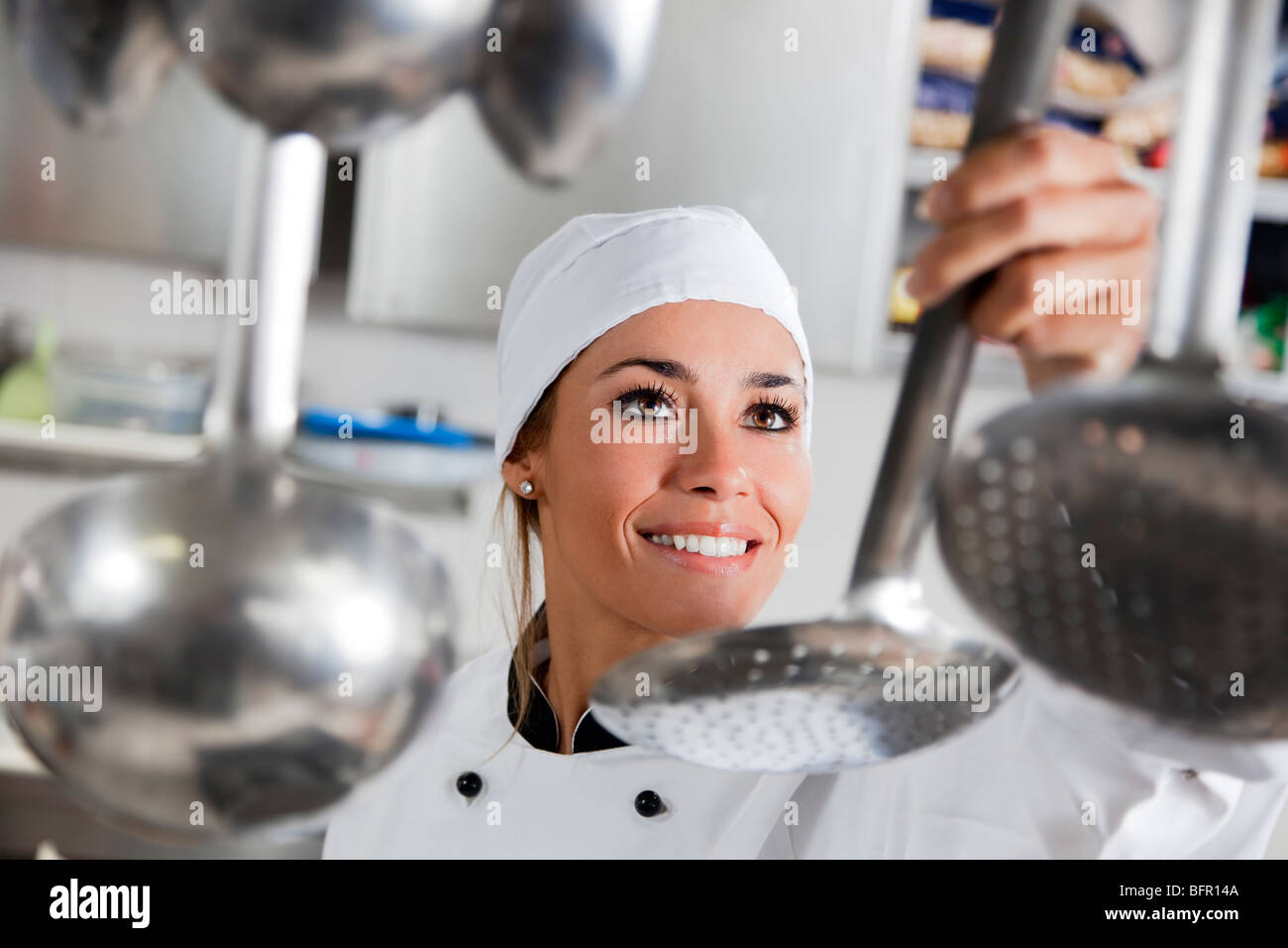 Mid adult female chef prenant ustensile de cuisine Banque D'Images