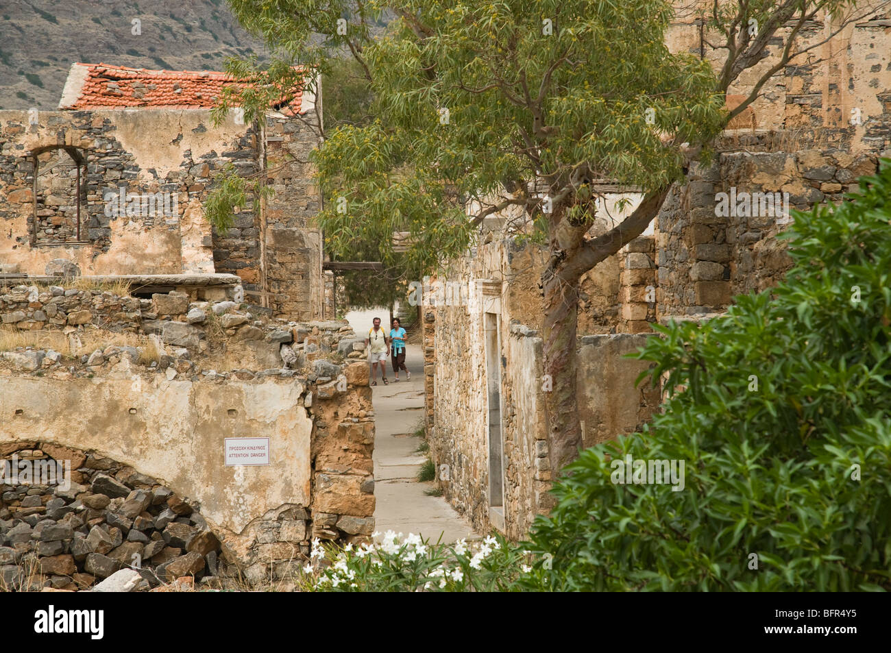 Dh Spinalonga AGIOS NIKOLAOS Grèce Crète les touristes à pied à travers des rues de l'ancienne léproserie en couple Banque D'Images