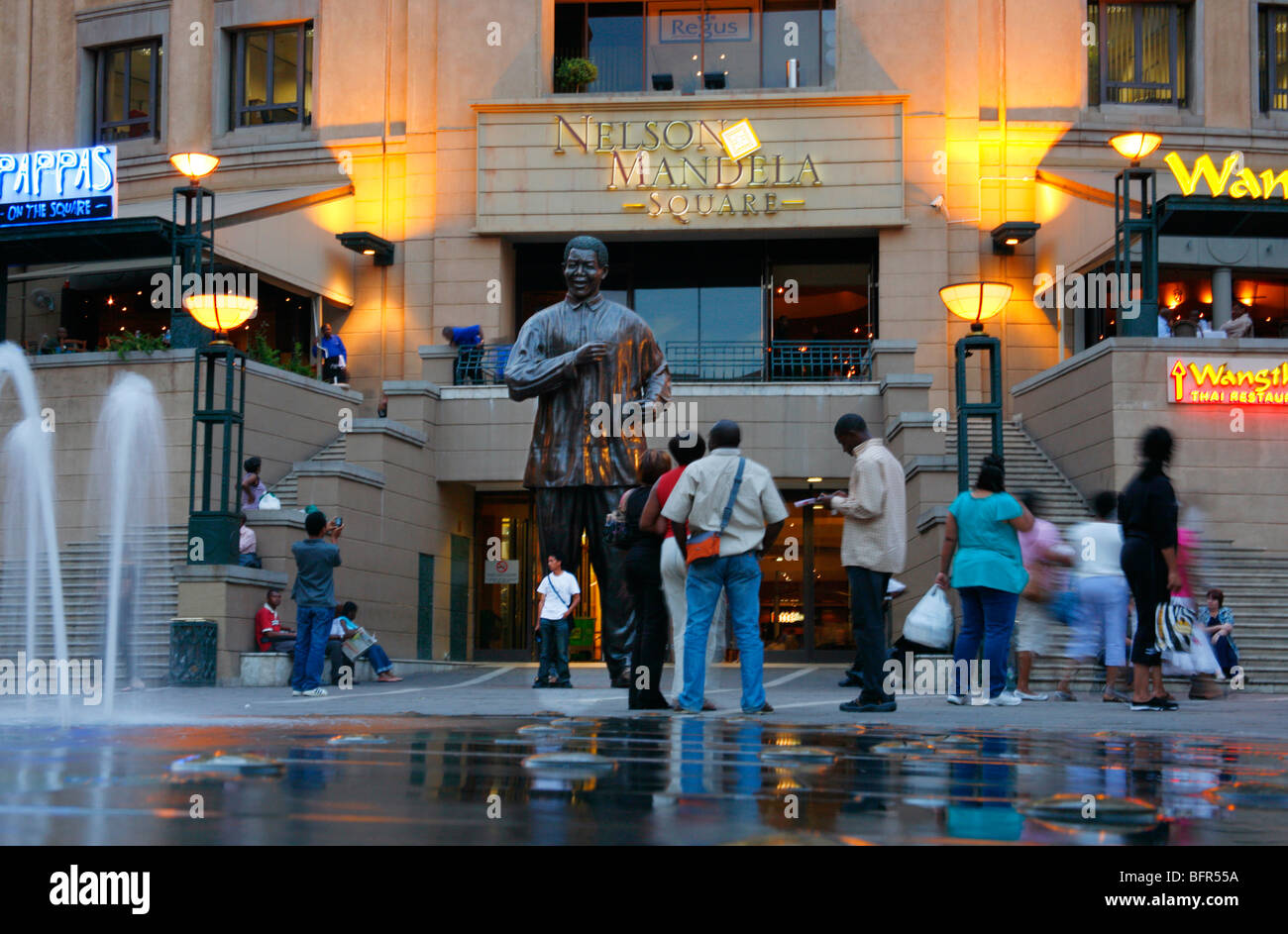 Les touristes se faisant passer à côté d'une statue de Nelson Mandela à la place Mandela à Sandton Banque D'Images