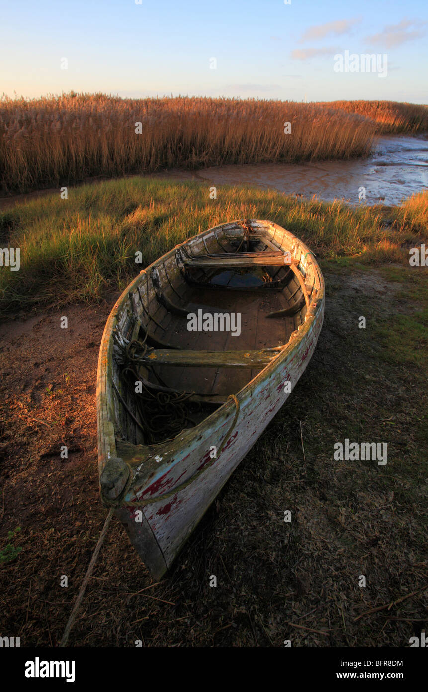 Un bateau en bois à Brancaster Staithe sur la côte nord du comté de Norfolk, avec des roseaux ensoleillée à l'arrière-plan. Banque D'Images