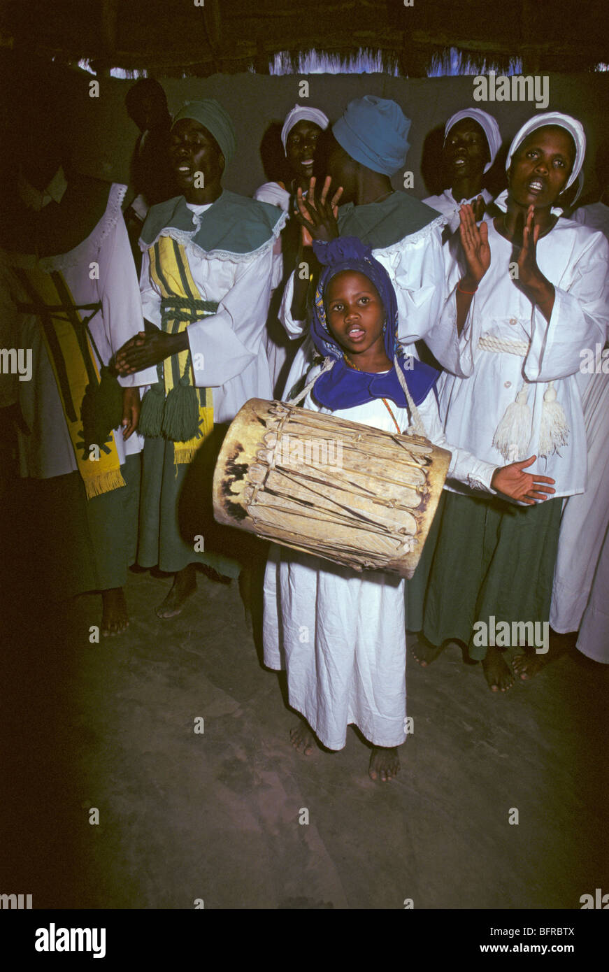 Jeune fille jouant un tambour avec le choeur de l'église de guérison du Botswana applaudissant et chantant Banque D'Images