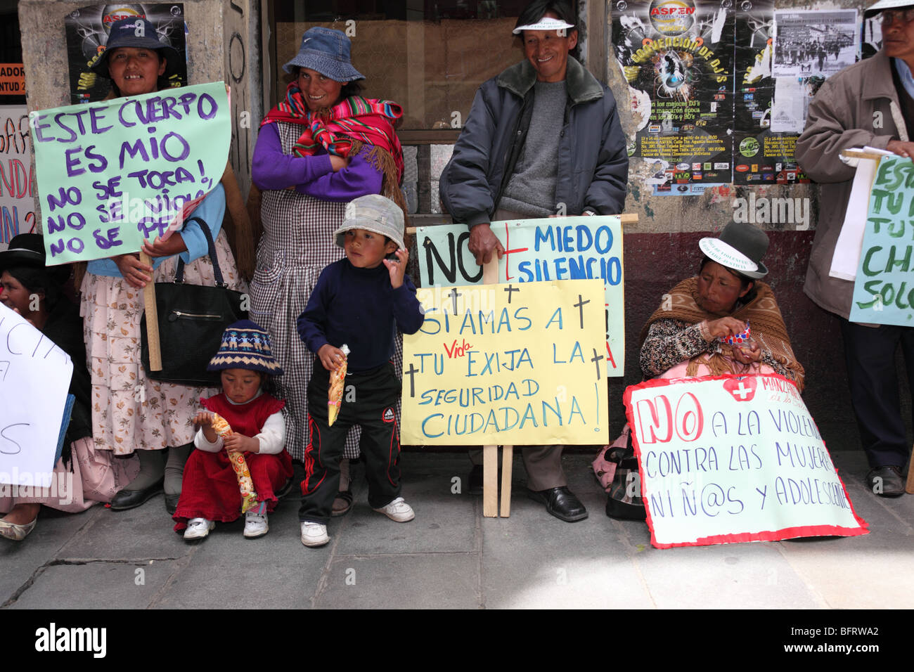 Famille Aymara debout sur le trottoir avec des pancartes lors d'une marche pour la Journée internationale de la non-violence à l'égard des femmes (25 novembre), la Paz, Bolivie Banque D'Images