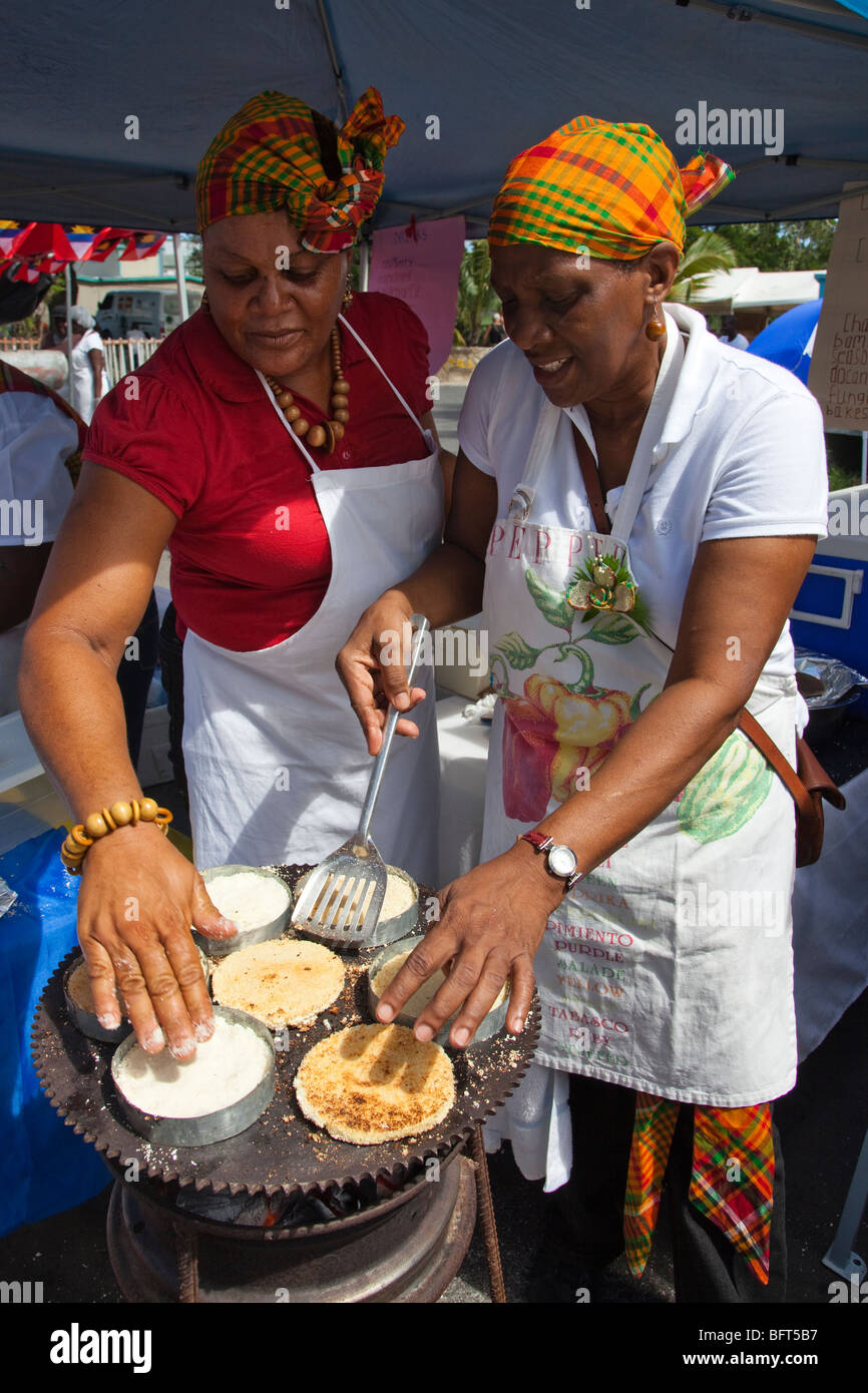 Deux femmes la cuisson des crêpes du manioc sur un grill ouvert durant la fête de l'indépendance fêtes, St Johns, Antigua-et-Barbuda Banque D'Images