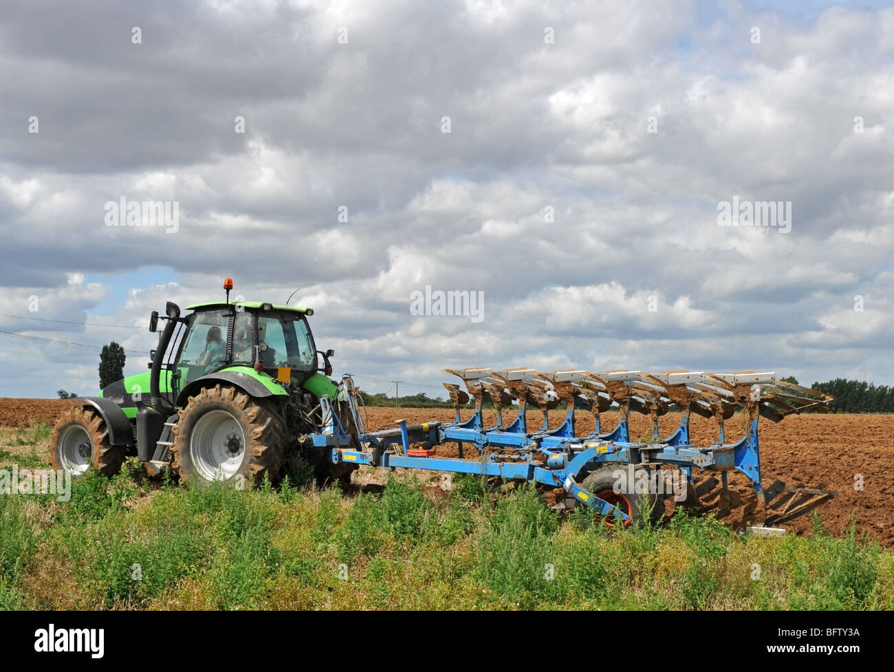 Tracteur laboure un champ vert prêts pour la plantation. Banque D'Images