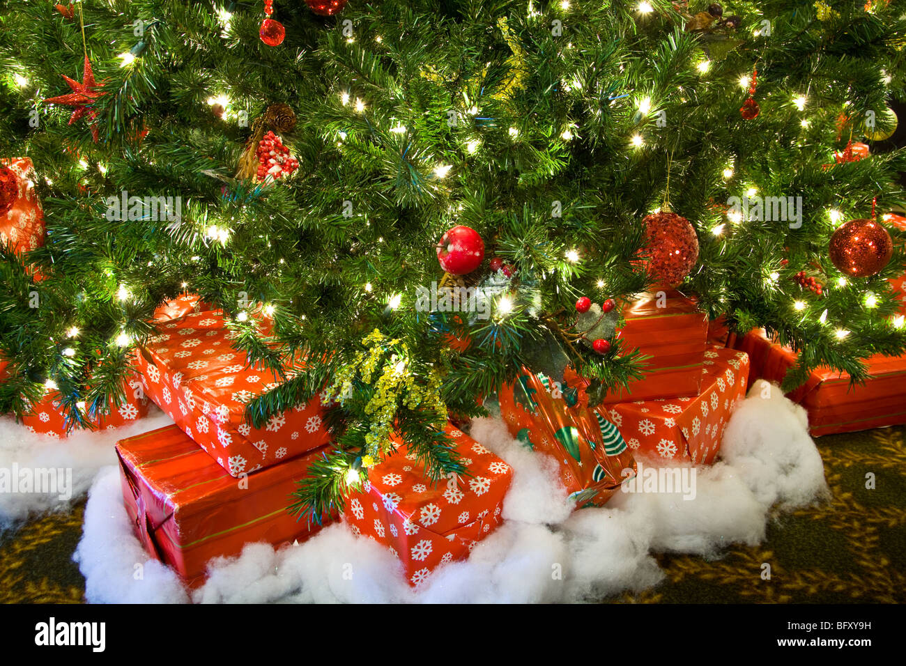Un tas de cadeaux de Noël sous un arbre éclairé. Banque D'Images