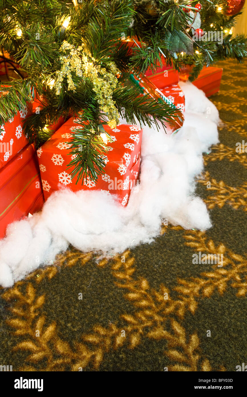 Des cadeaux de Noël sous un arbre de Noël, entouré de tapis avec la conception de l'or. Banque D'Images
