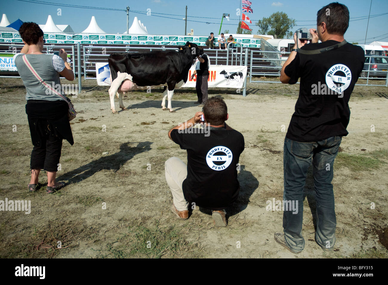 Les travailleurs français des produits laitiers dans la région de tee-shirts avec un slogan d'alarme commerce lait de photographier une vache Holstein primés lors d'une foire gasconne Banque D'Images