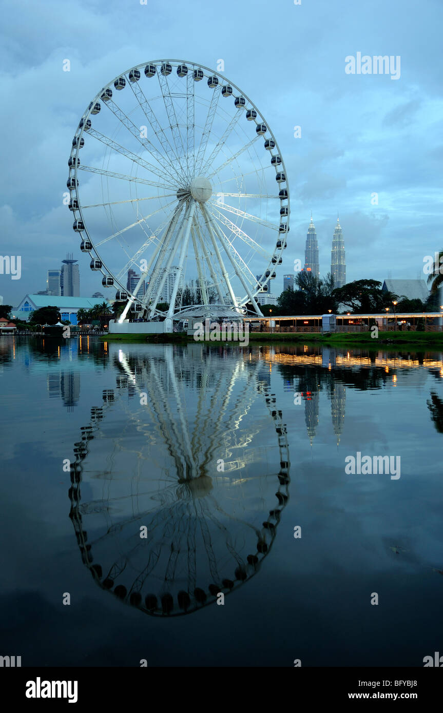 La grande roue, l'œil sur la Malaisie, se reflète dans les jardins du lac Titiwangsa, avec les tours Petronas au loin, Kuala Lumpur, Malaisie Banque D'Images