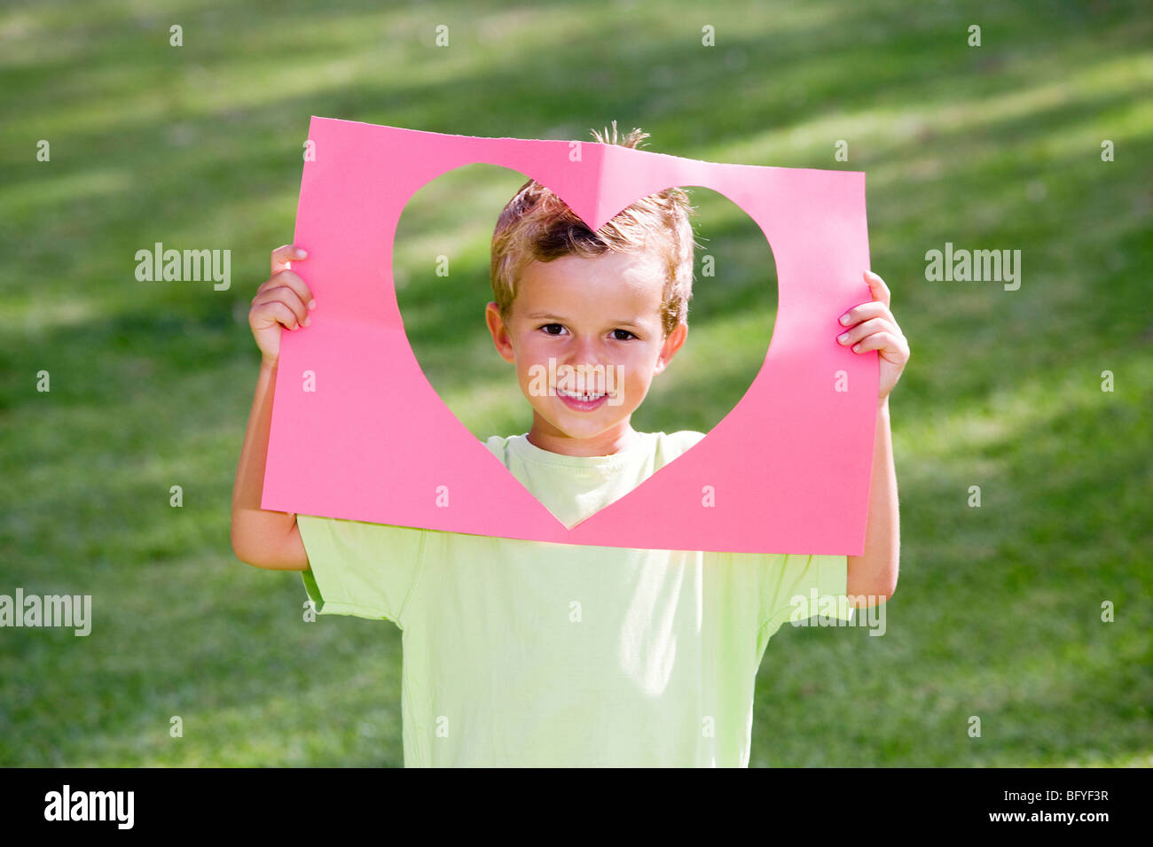 Young boy holding paper heart frame Banque D'Images