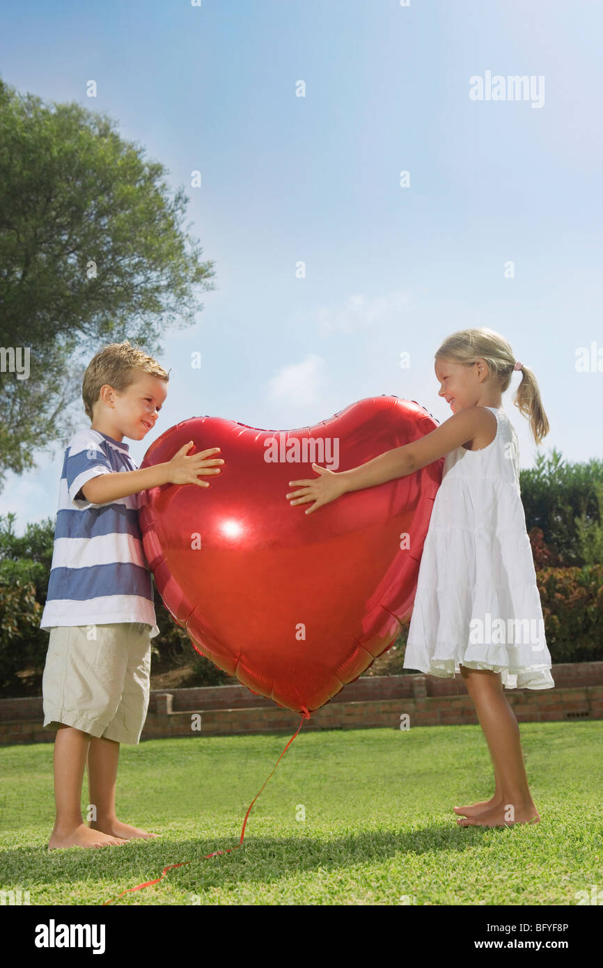 Les jeunes enfants serrant ballon coeur rouge Banque D'Images