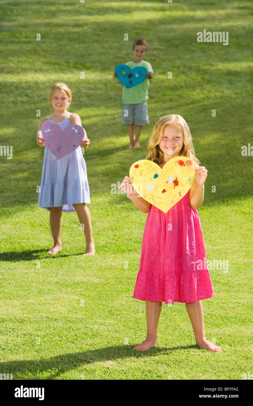 Les jeunes enfants holding paper hearts Banque D'Images