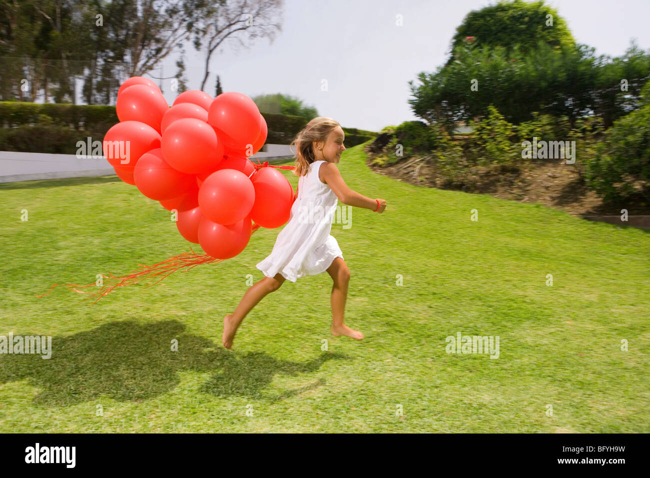 Jeune fille courir avec des ballons rouges Banque D'Images