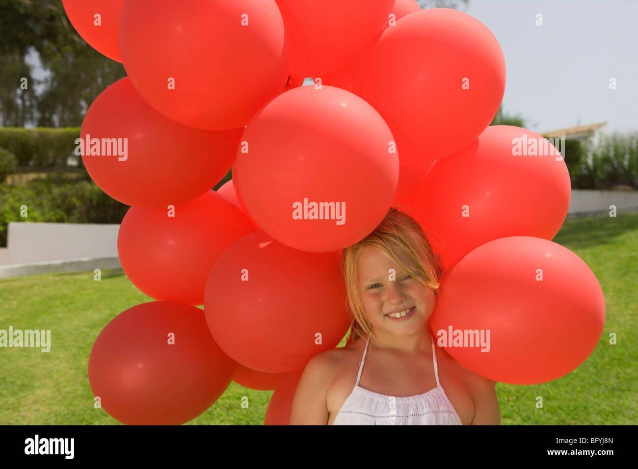 Young Girl holding bunch of red balloons Banque D'Images