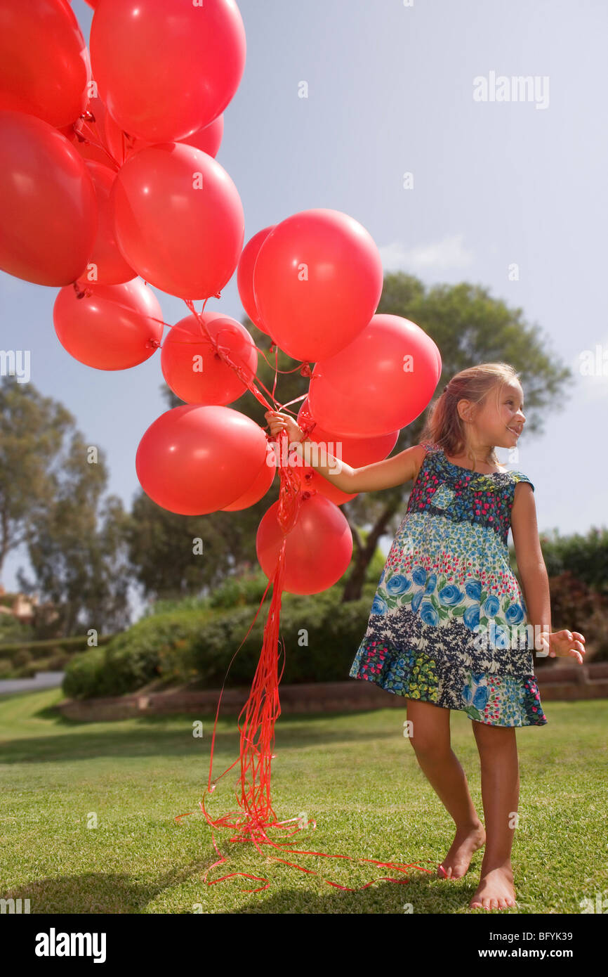 Young Girl holding bunch of red balloons Banque D'Images