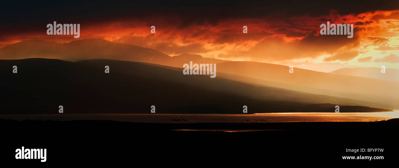 Superbe coucher de soleil rouge sur le Loch Shin mountain area, Sutherland, dans le Nord de l'Ecosse, Royaume-Uni prises à partir d'un format panoramique en838 Banque D'Images