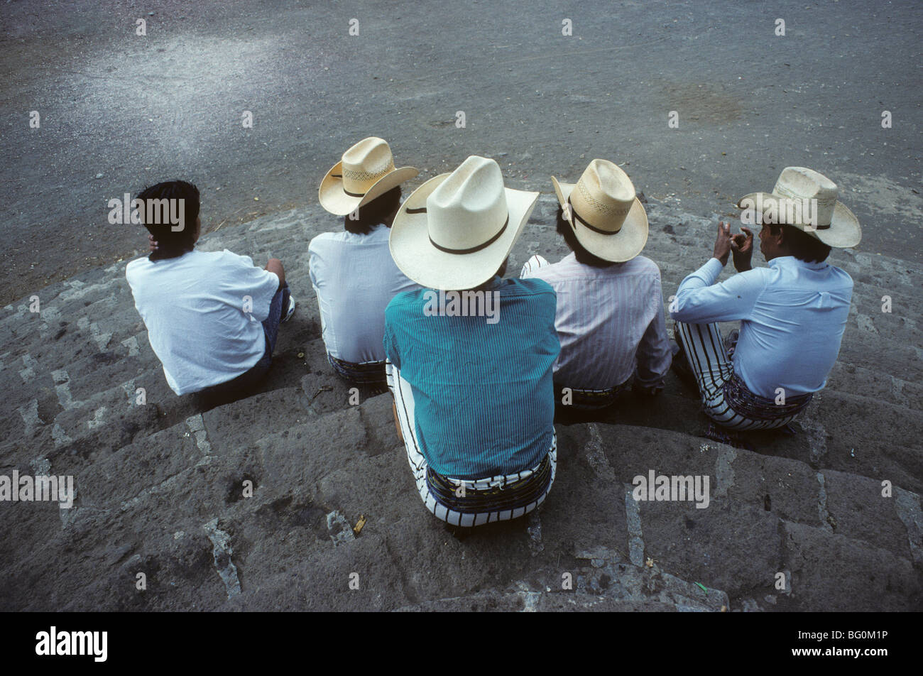 Un groupe d'hommes reste et engager la conversation sur les marches d'une église de Santiago Atitlan, Guatemala Banque D'Images