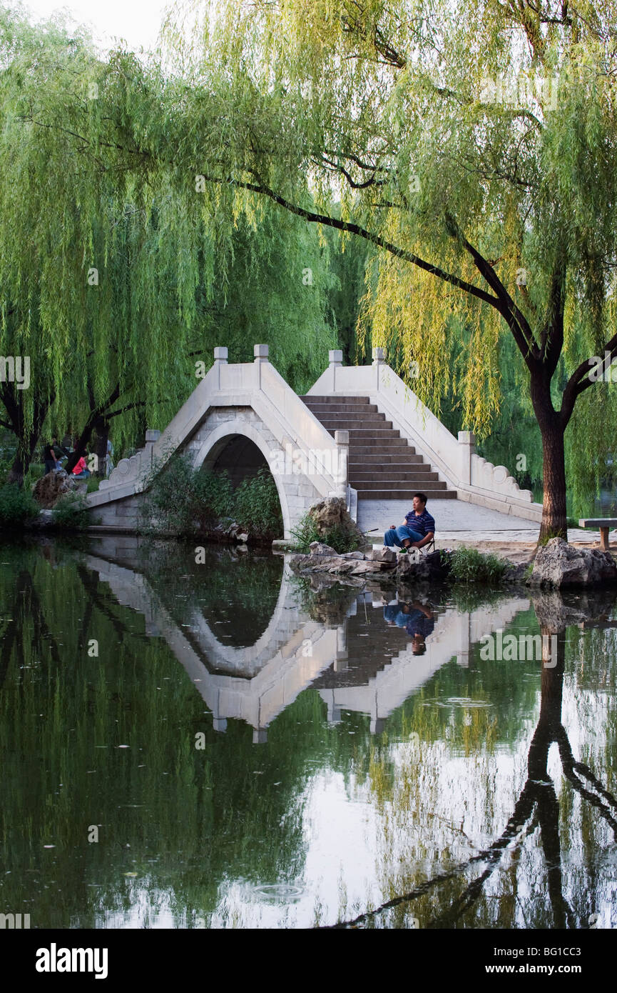 Pêche à l'homme à côté d'un pont voûté en pierre en bambou noir Zizhuyuan Park, Beijing, China, Asia Banque D'Images