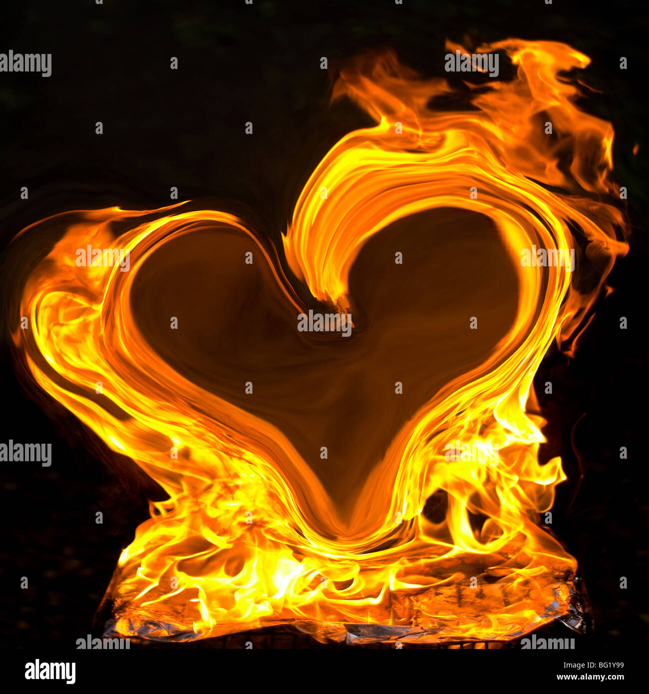 Les grandes flammes jaunes en forme de coeur sur fond noir Banque D'Images