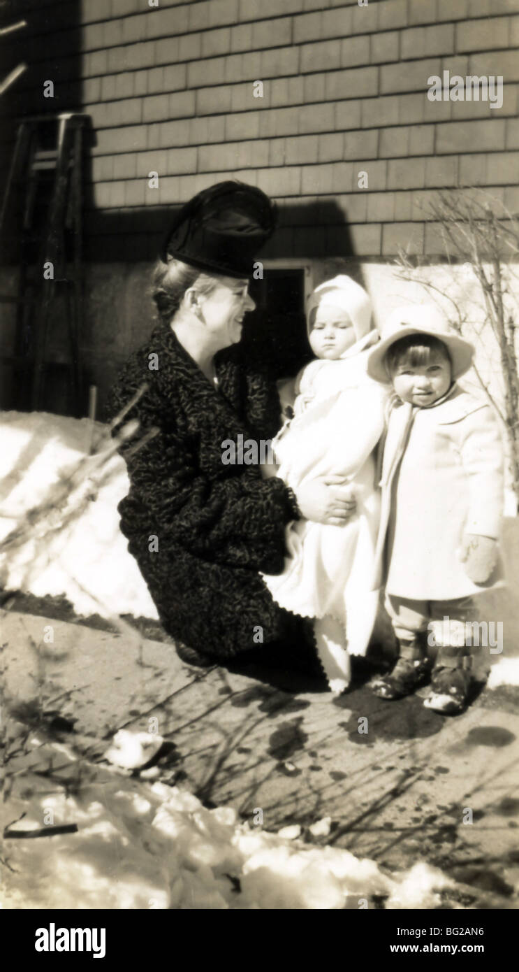 Une mère, tenant son fils et sa fille, à l'extérieur de leur maison à New Bedford, Massachusetts, l'hiver de 1947. Banque D'Images