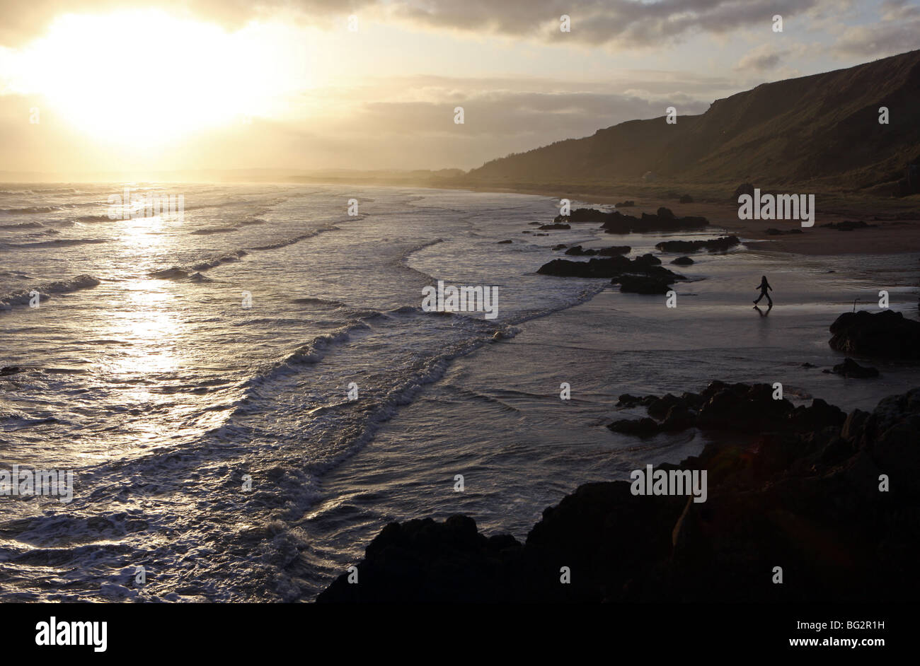 Lone walker sur une belle plage de sable de St Cyrus, Aberdeenshire, Scotland, UK, au coucher du soleil Banque D'Images