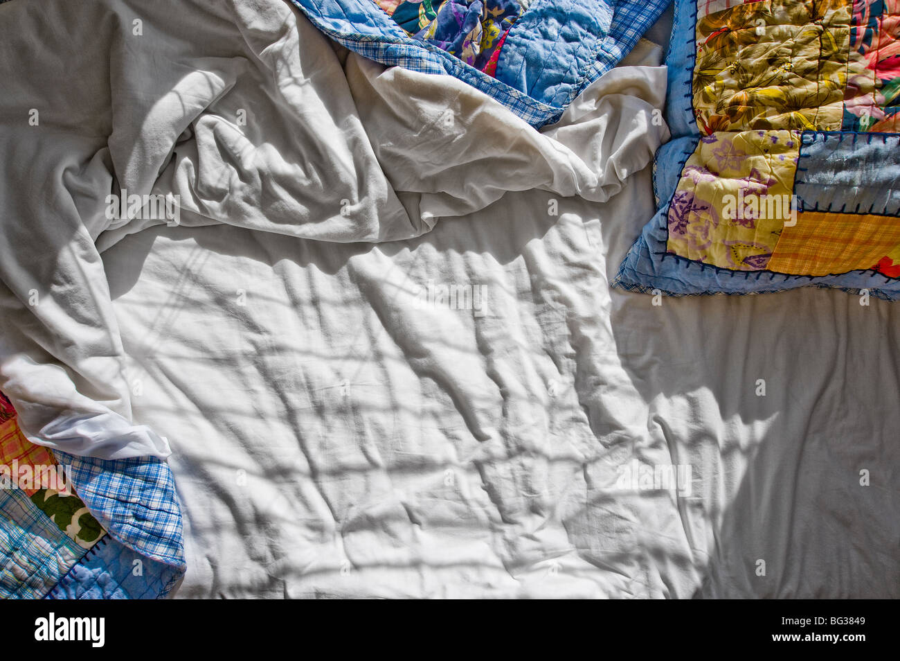 Messy lit avec draps froissés et des ombres Banque D'Images
