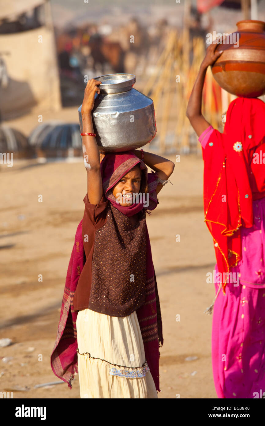 Fille de transporter l'eau sur sa tête à la foire de chameau à Pushkar Inde Banque D'Images