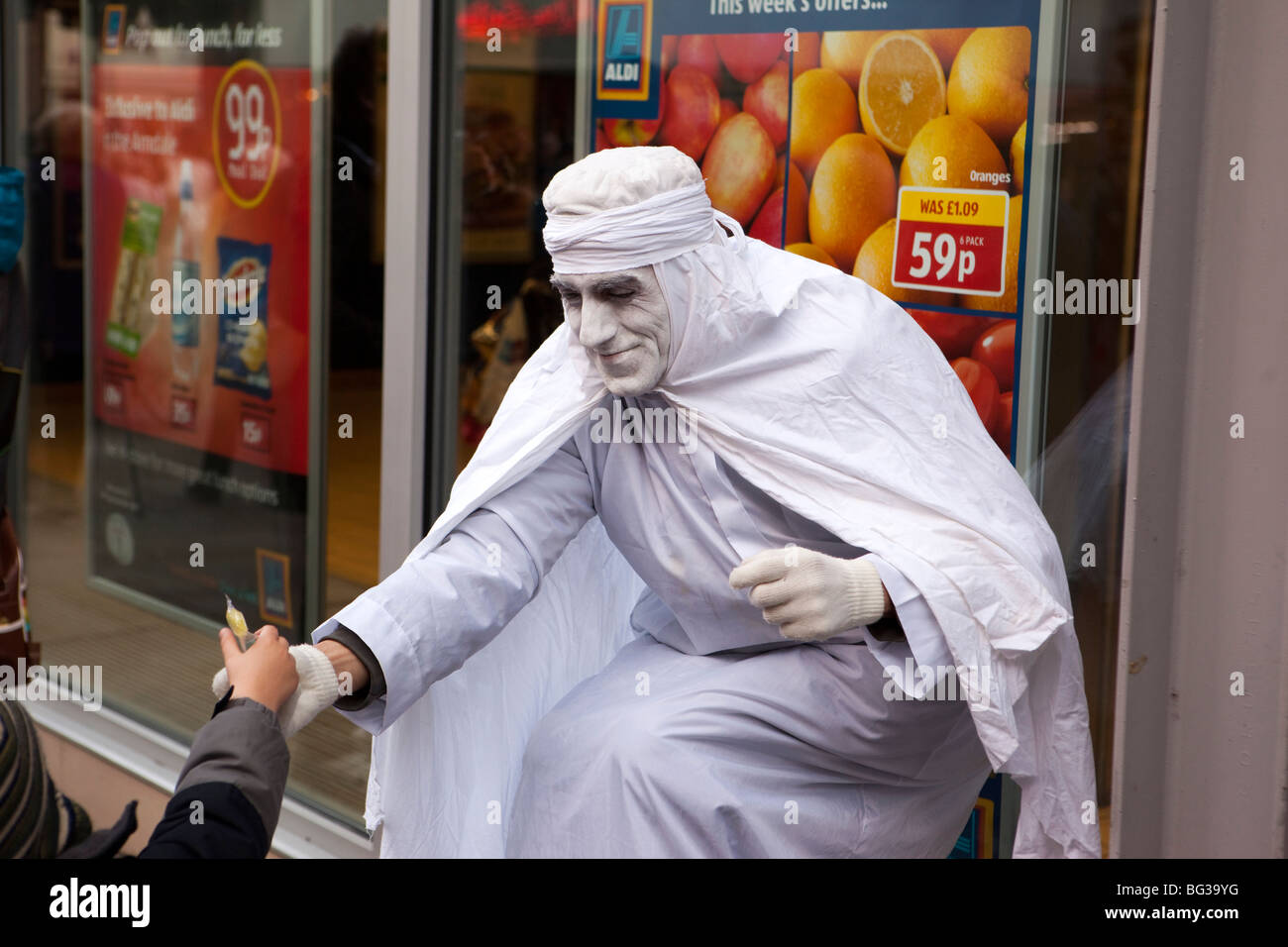 Royaume-uni, Angleterre, Manchester, Market Street, blanc habillé de busker statue à l'enfant doux donnant Banque D'Images