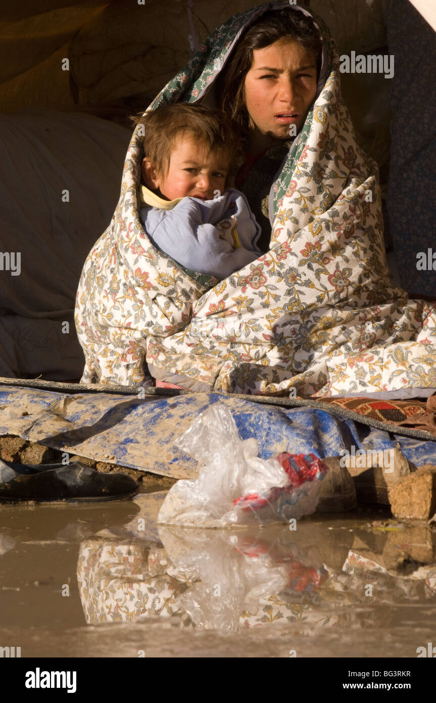 Bravant le froid de l'enfant afghan dans une tente dans la ville de Kaboul, Afghanistan. Banque D'Images
