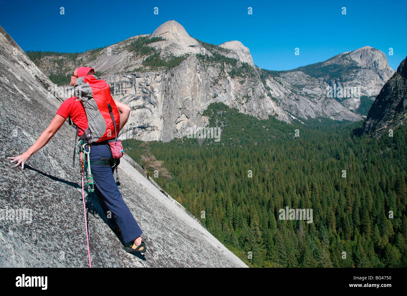 Climber dalles monte à la base de l'immense falaise appelée l'aire, et la colonne de Washington au Nord Dome, Yosemite Valley, California, USA Banque D'Images