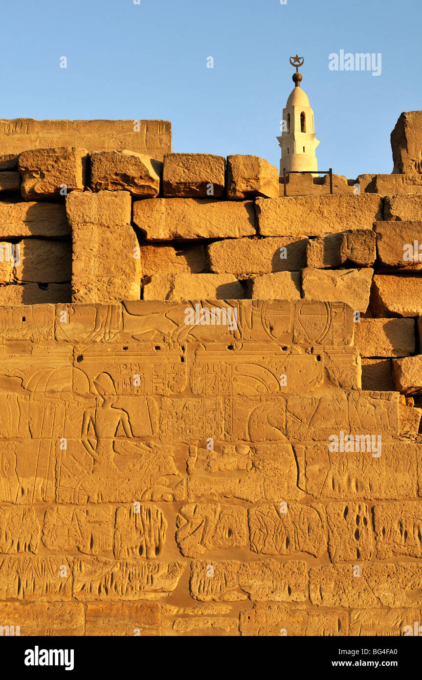 Sur le mur de sculptures cour de Ramsès II avec Minaret de mosquée d'Abou el-Haggag en arrière-plan, temple de Louxor, Egypte Banque D'Images