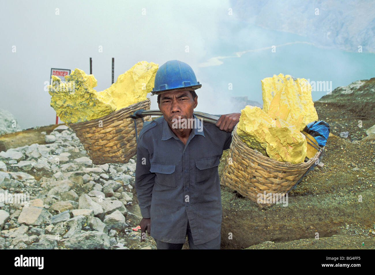 Homme engagé dans l'exploitation minière, de soufre un travail dangereux et de rupture dans le Kawah Ijen, cratère du volcan Ijen, Java Est, Indonésie Banque D'Images