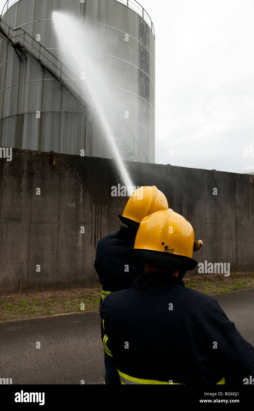 Les pompiers l'application de la mousse pour les réservoirs de stockage d'huile à la raffinerie d'huile Banque D'Images