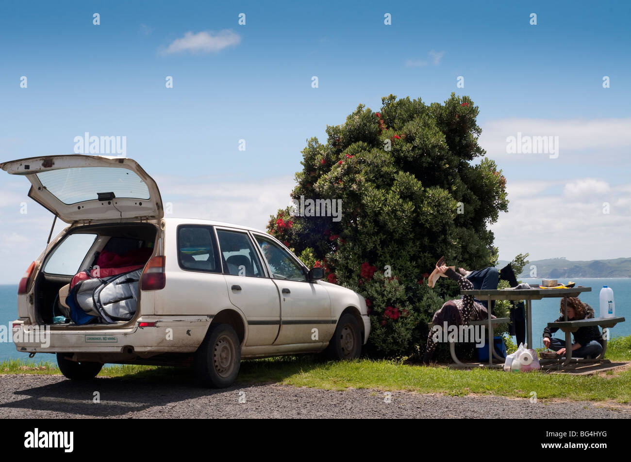 Garé camionnette pleine de planches de plus à l'océan, avec deux femmes prises dans la cuisine et la lecture de Raglan, Nouvelle-Zélande Banque D'Images
