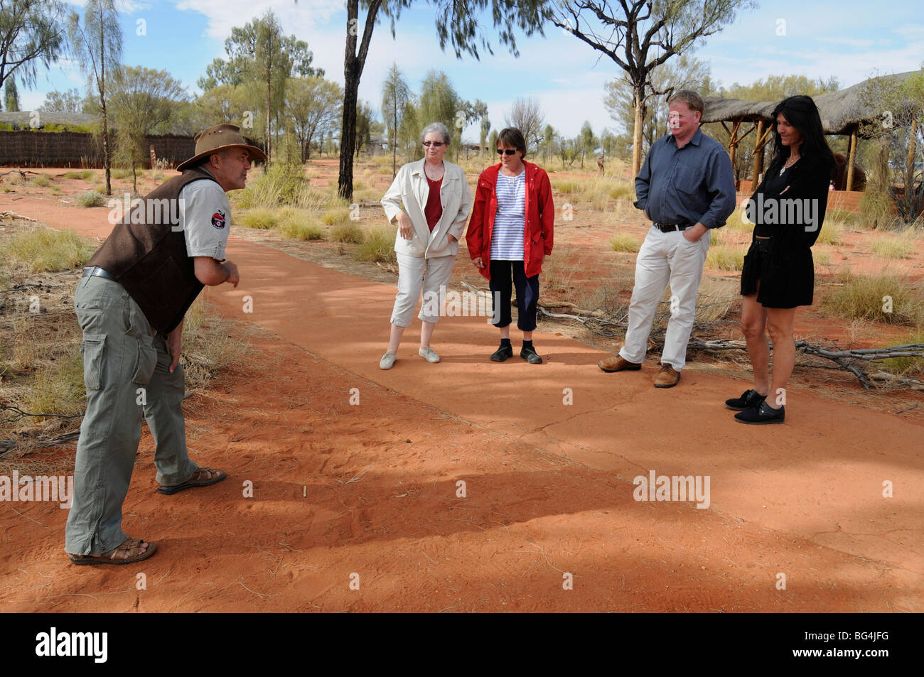 Un gardien explique la méthode de suivi des animaux sur les Autochtones à une partie des visiteurs à Uluru - Kata Tjuta National Park, Australie. Banque D'Images