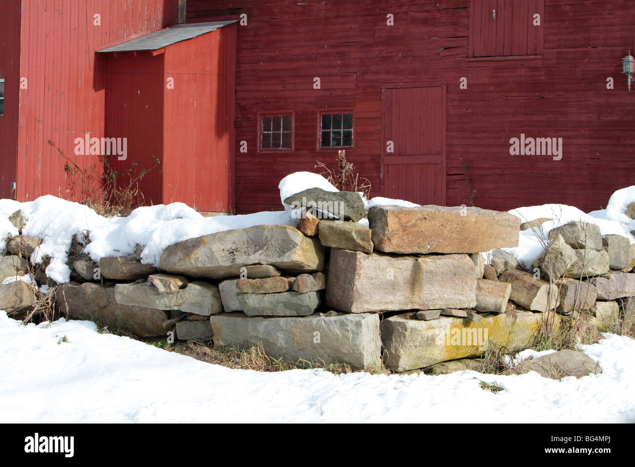 Une vieille grange rouge vintage avec un mur de pierre. Banque D'Images