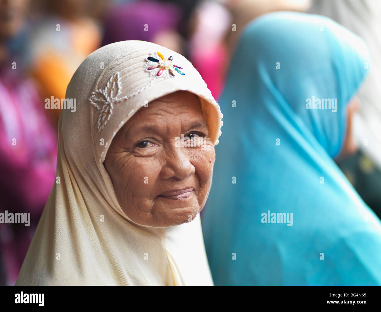 Une femme musulmane âgée souriante portant un hijab brodé. Banque D'Images