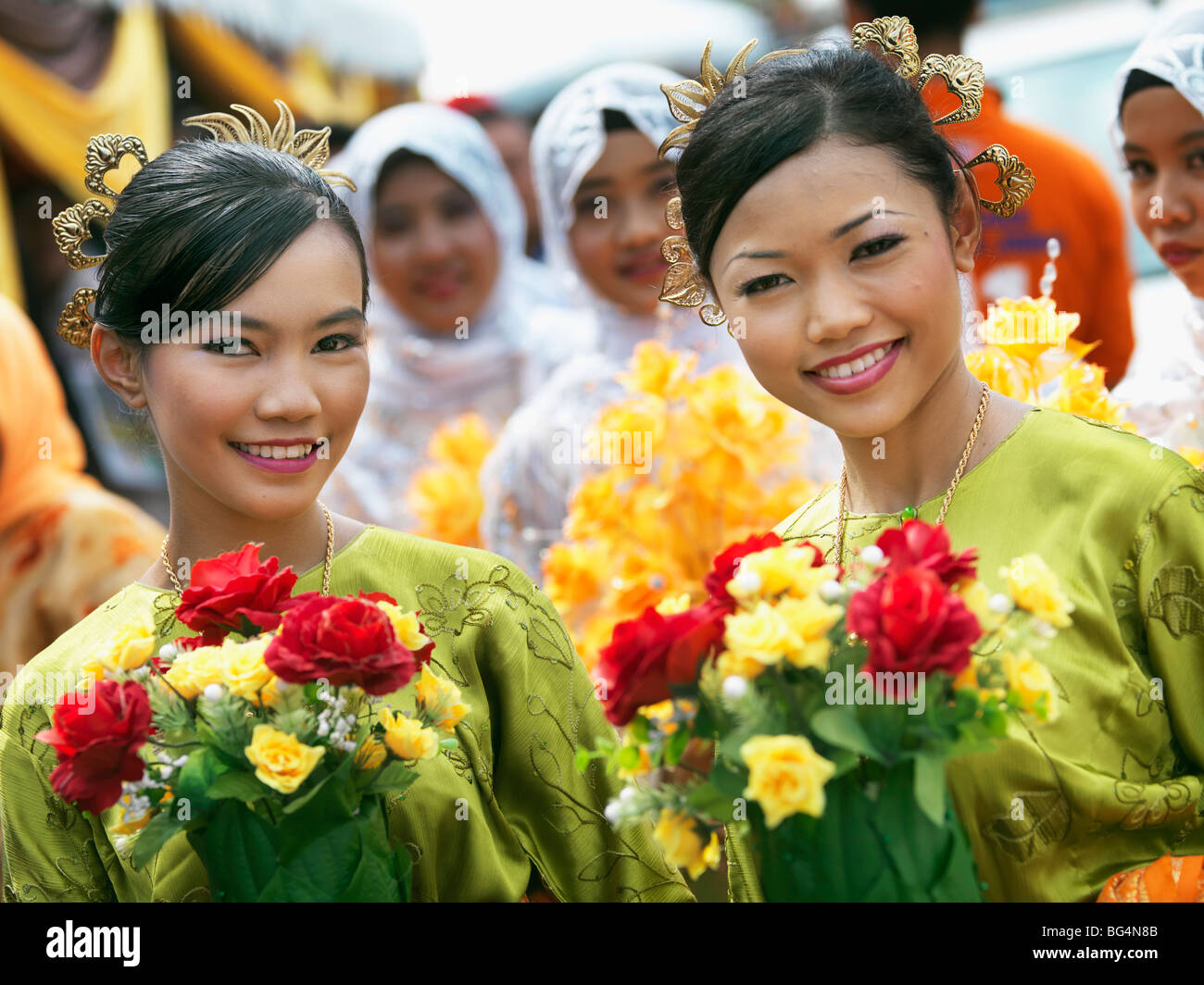 Deux jeunes femme en tenue de cérémonie tenue des bouquets de fleurs. Banque D'Images