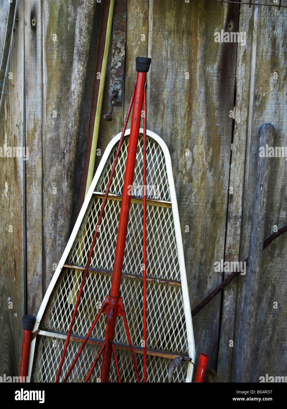Le rouge et le blanc planche appuyée sur un mur en bois avec poignée à côté de râteau Banque D'Images