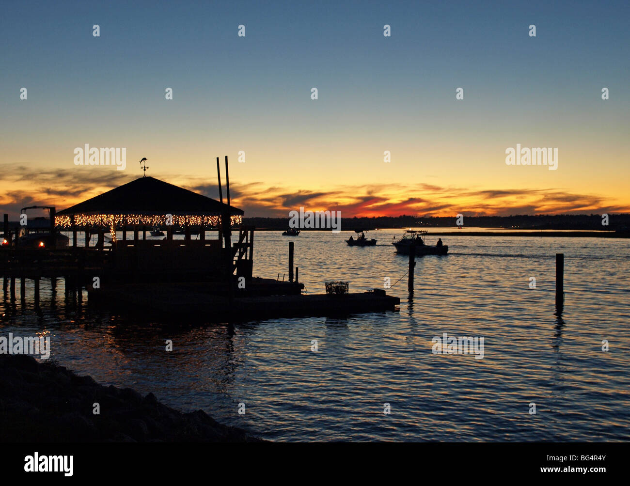 Vue du coucher de la voie navigable intercoastal sound dock et bateaux avec des lumières de Noël orange et bleu ciel Banque D'Images