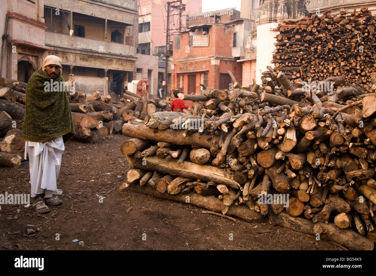 Dom, un membre de la caste hindoue qui conduit des cérémonies de crémation, les peuplements de bois empilé par le Marnikarnika Ghat de Varanasi. Banque D'Images