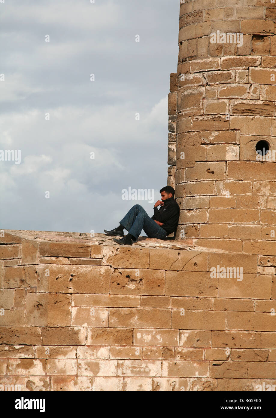 Homme assis sur les remparts, murs Skala de la ville, Essaouira, Maroc Banque D'Images