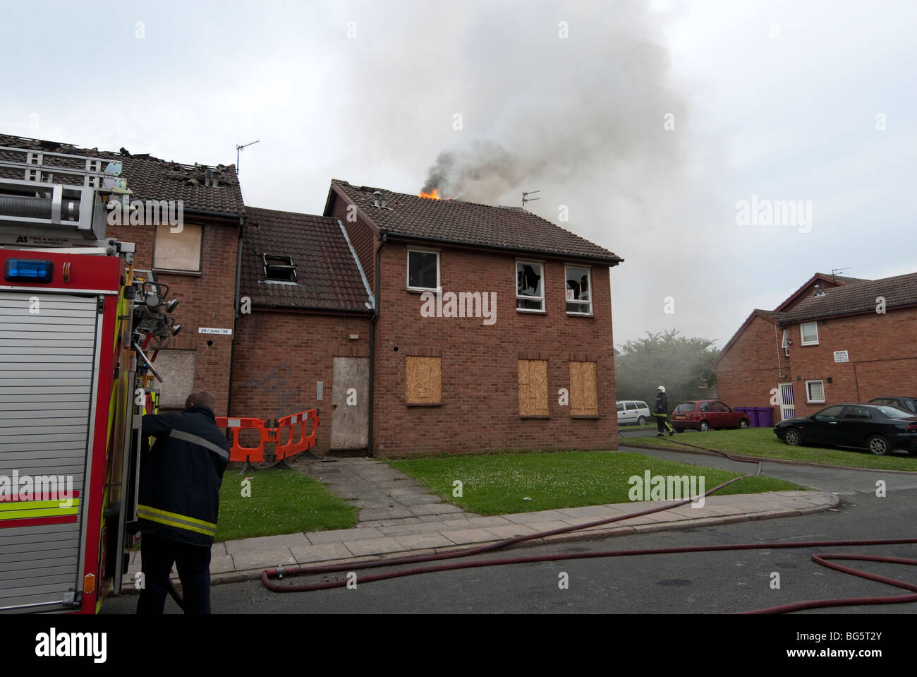 Toit de maison en feu avec Fire Engine en premier plan Banque D'Images