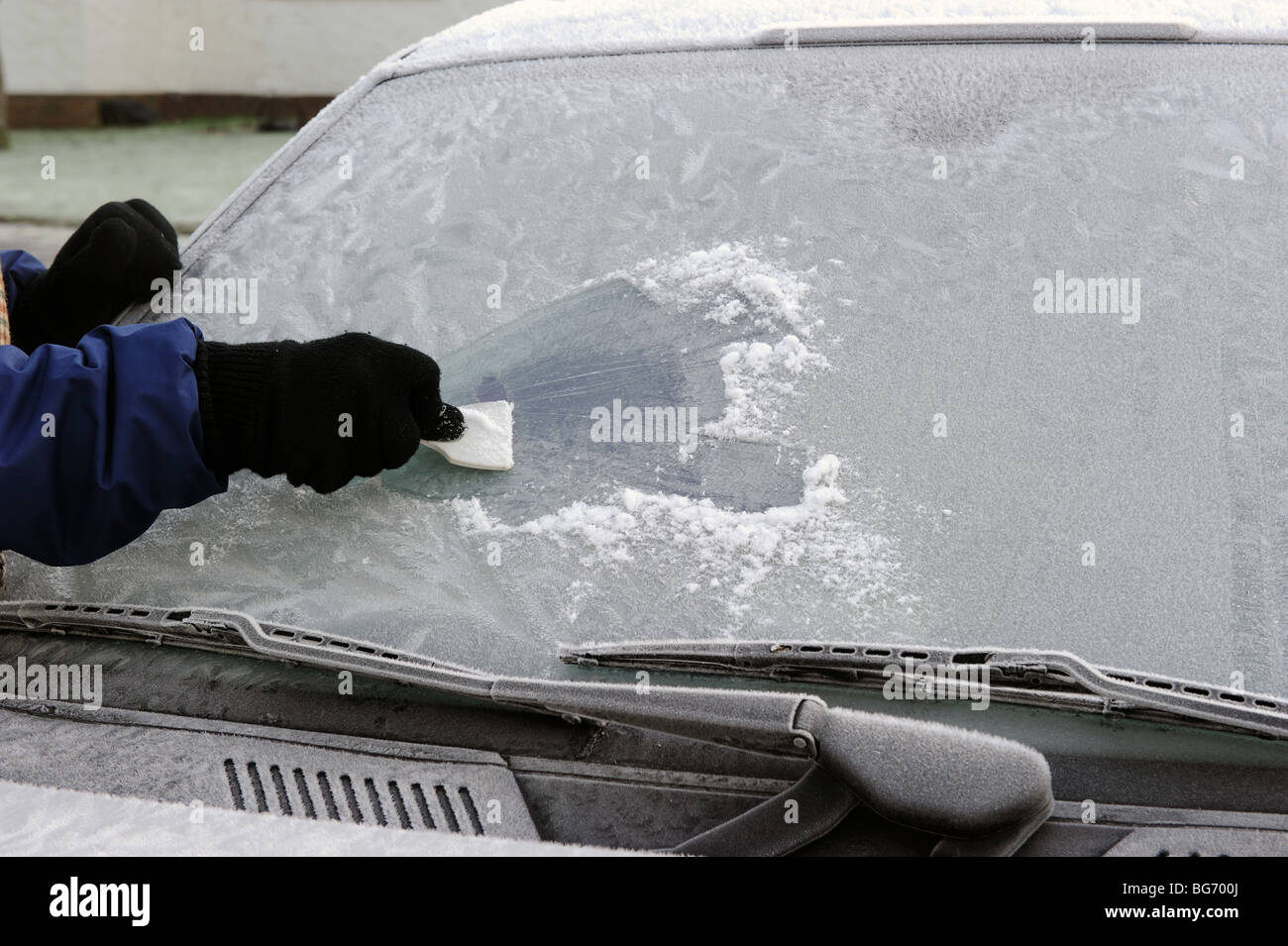 Le grattage d'un pare-brise de voiture givrée sur un matin d'hiver Banque D'Images