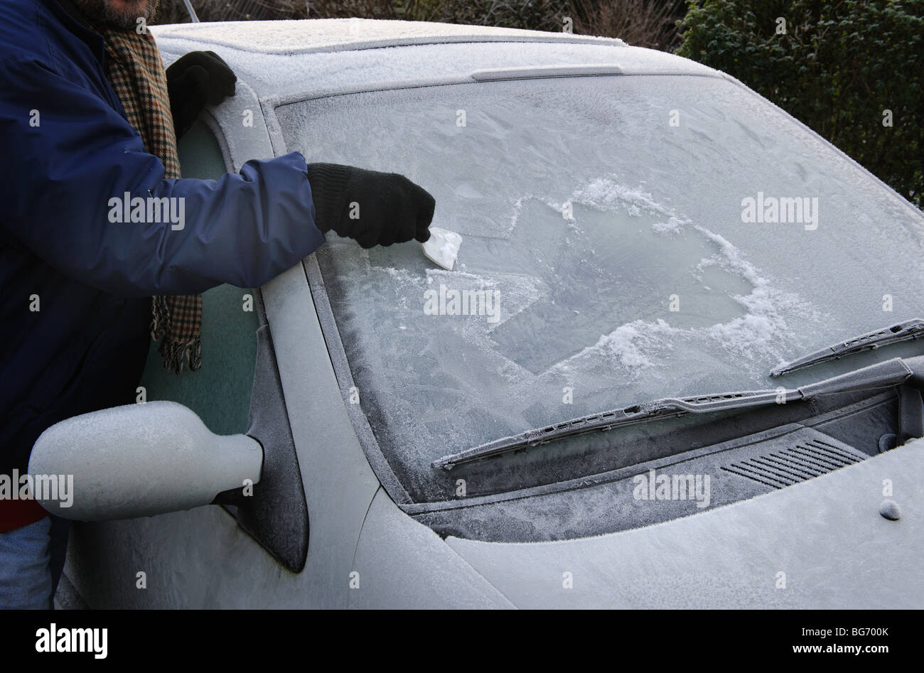 L'homme Nettoie Une Vitre Glacée Sur Une Voiture Avec Un Grattoir à Glace  Froid Matin Enneigé Et Glacial